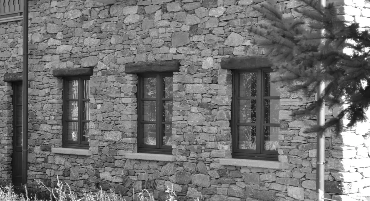 Finestre in legno su facciata in pietra, restauro conservativo di casa piemontese tradizionale